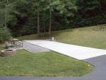 A concrete RV site with a bench and fire pit at CREEKWOOD RESORT - thumbnail