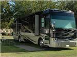 A Class A motorhome parked in a grassy site at SUGAR BARGE RV RESORT AND MARINA - thumbnail