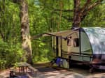 A travel trailer in a shady site - thumbnail