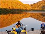 View larger image of A man playing a guitar next to the water at GROS MORNENORRIS POINT KOA image #5