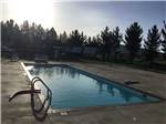 View larger image of Swimming pool at campground with setting sun reflecting on its surface at LOST ALASKAN RV PARK image #1
