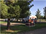 View larger image of Tan and red small trailer parked behind brick picnic table at LOST ALASKAN RV PARK image #6