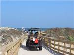 A couple in a golf cart driving in a path to the beach at PIONEER BEACH RESORT - thumbnail