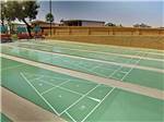 View larger image of Green shuffleboard courts surrounded by a brick wall and trees at SUNRISE RV RESORT image #12