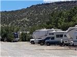 RVs parked on site with large hill in distance at BAR S RV PARK - thumbnail