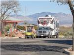 View larger image of A golf cart leading a Fifth wheel to a RV site at CT RV RESORT image #1