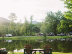 Adirondack chairs by the water at Mountain River Family Campground - thumbnail