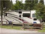 A motorhome parked in a site with chairs next to it at COLUMBIA FALLS RV PARK - thumbnail