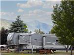 A fifth wheel in a gravel site next to a picnic bench at COLUMBIA FALLS RV PARK - thumbnail