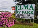View larger image of Park sign next to pink flowers and Good Sam sign at ELMA RV PARK image #1