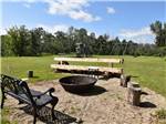 A fire pit with a playground in the background at COUNTRY ROADS RV PARK - thumbnail