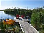 A paddleboat near the dock with two chairs at COUNTRY ROADS RV PARK - thumbnail