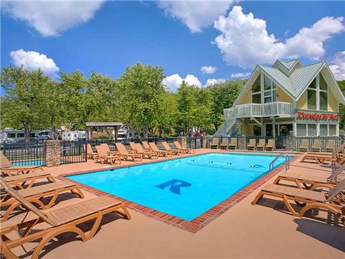 Large pool and lounge chairs outside main building at RIVEREDGE RV PARK & CABIN RENTALS