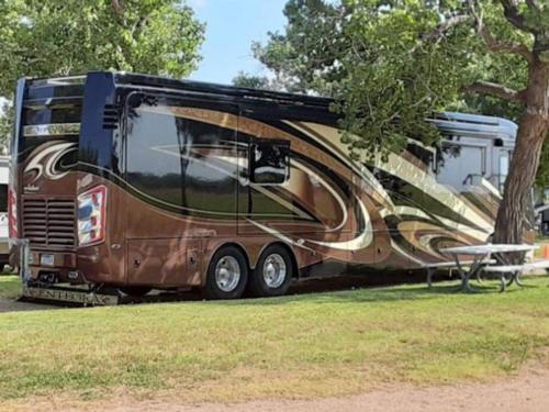 Large rig parked at a shaded site at SEVEN WINDS RV PARK