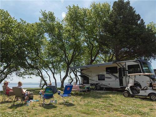 A couple sitting on chairs next to their motorhome at OUTER BANKS WEST/CURRITUCK SOUND KOA HOLIDAY