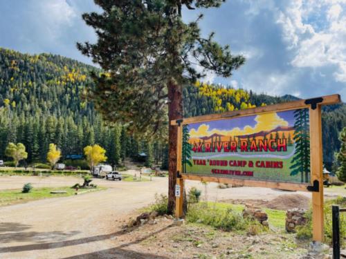 Brightly colored sign in front of a hill covered in pine trees at 4K River Ranch