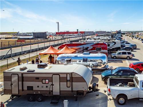 Travel trailers lined up next to the racing track at COTA CAMPING-PREMIUM RV PARK