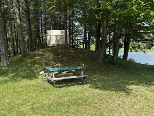 A shaded campsite with water view at Wake in the Woods Aquapark & Campground
