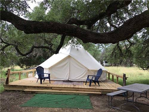 A glamping tent with lounge chairs in front of it at REBECCA CREEK CAMPGROUNDS