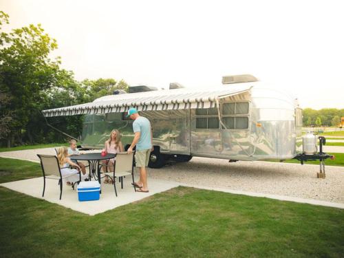 A family sitting next to their Airstream at CAMP LANDA RV RESORT