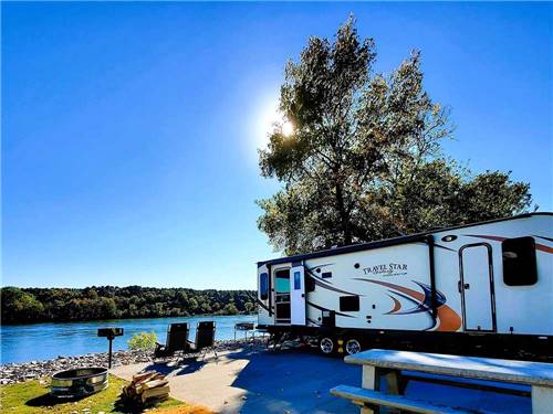 A trailer backed in with a river view at BOTEL CAMPGROUND