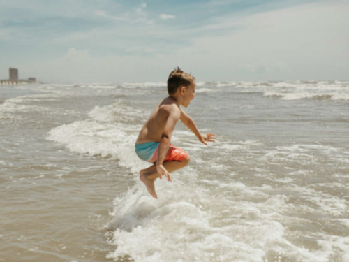 Child jumping in the waves at Corpus Christi Boardwalk RV Park