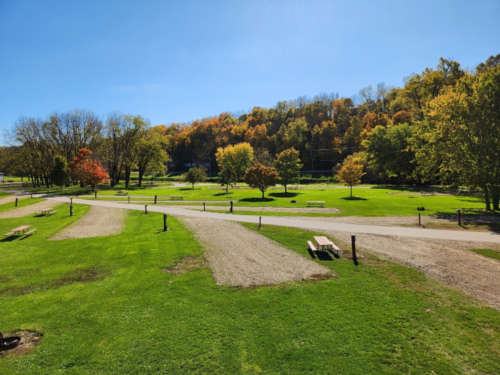 Tree lined RV sites with picnic tables at Pecatonica River Trails Park