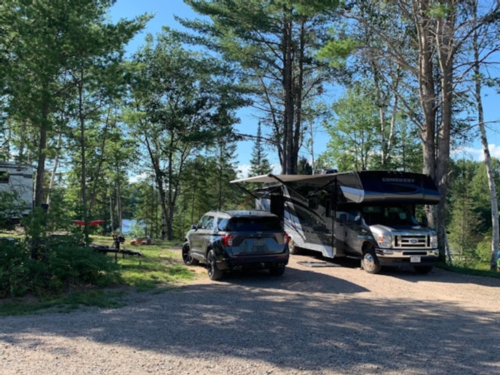 SUV and RV in gravel site at Wildwood Outdoor Adventures and Campground