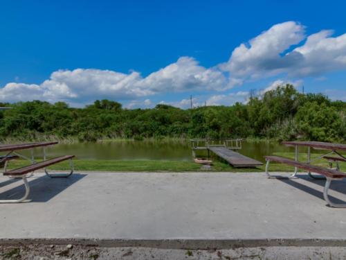 Patio, picnic tables and pond with dock at Lake Corpus Christi RV Resort