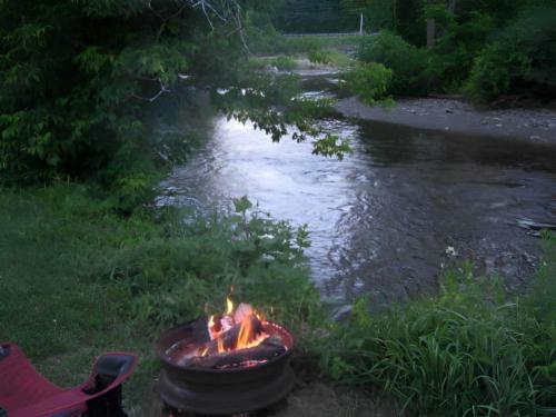 Fire pit in front of creek at site Onion River Campground
