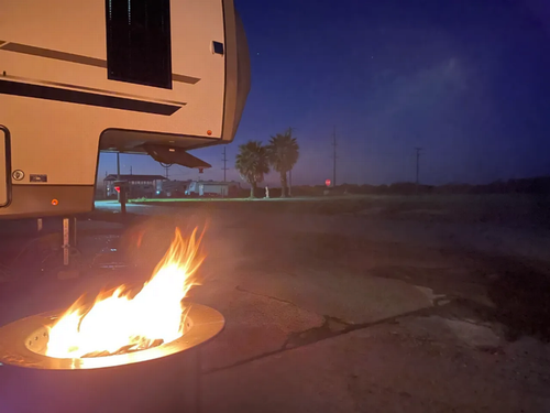 A fire ring near an RV at site at Holly Beach RV Park