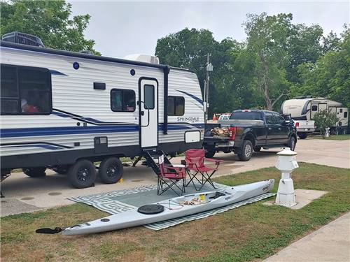 An RV parked at site with seating and kayak