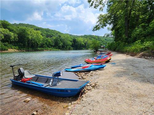 Kayaks and boats in a row at the river at BSC OUTDOORS CAMPING & FLOAT TRIPS