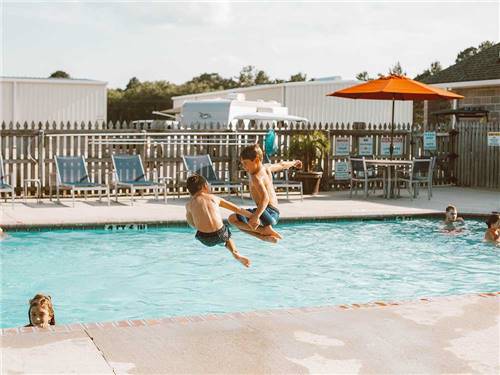 A couple of boys jumping into the pool at LAKESIDE RV RESORT BY RJOURNEY