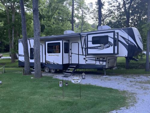 A 5th wheel parked in a shady site