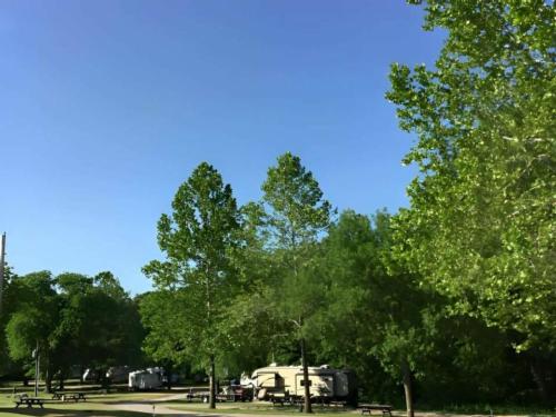 Travel trailers parked at sites among trees at Pony Express RV Park & Campground