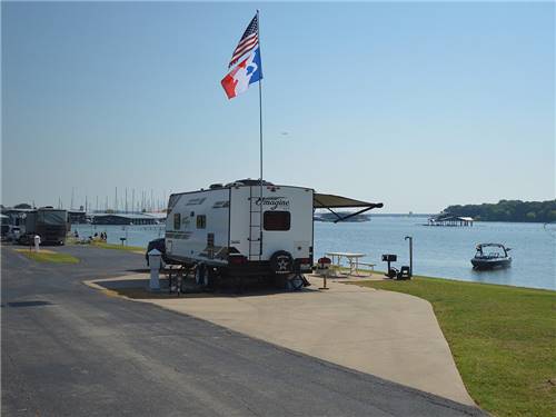 Fifth wheel trailer parked in site next to the lake at The Vineyards Campground & Cabins