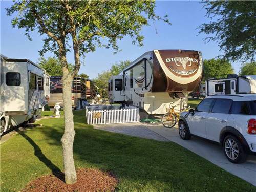 A fifth wheel trailer and car in an RV site at GERONIMO RV PARK