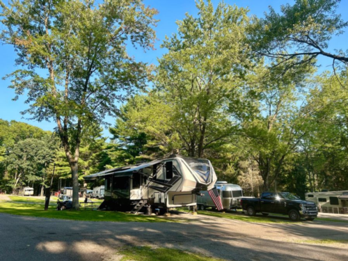 Camper by trees at Rustic Acres RV Resort & Campground