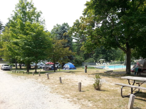 Tent in site and pool area at Winding River Campground