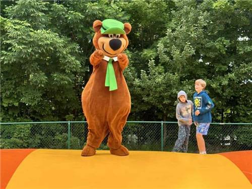 Yogi Bear and two kids on the jumping pillow at JELLYSTONE PARK ™ AT BIRCHWOOD ACRES