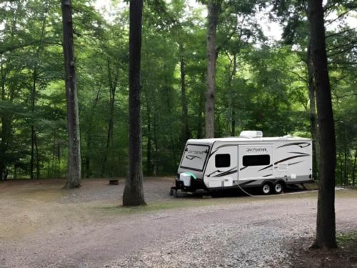Trailer parked near woods at site Wolf's Den Family Campground