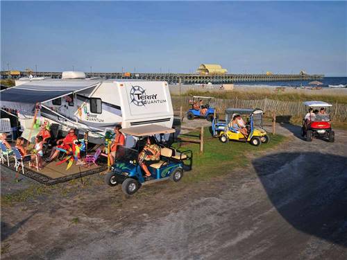 A group of people driving golf carts around at APACHE FAMILY CAMPGROUND & PIER