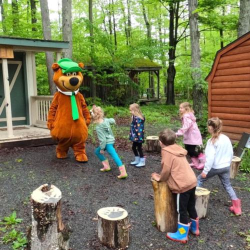 Yogi Bear in front of cabin at site Jellystone PA Wilds